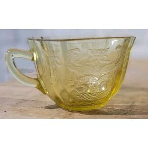 Yellow depression glass teacup with embossed filigree on the outside. Mold-blown